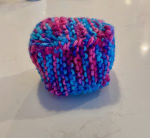 a 3D cube knitted from blue and pink yarn