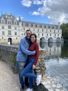 a couple standing in front of a historic castle in France