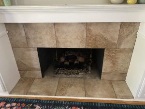 a fireplace with beige tile and a white mantle