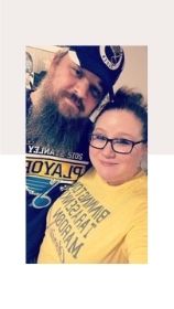 a man and a woman wearing St. Louis Blues t-shirts as they pose together for a picture