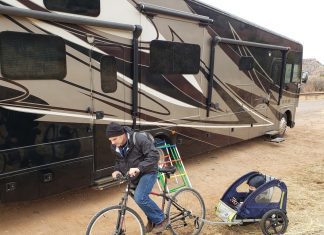 a dad on a bike pulling his son behind him next to an RV