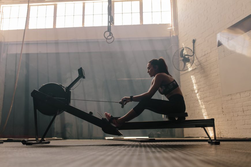 a woman in a warehouse gym on a rowing machine