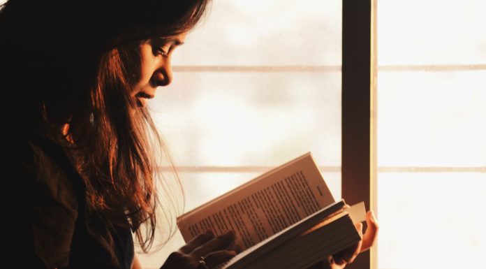 a woman sitting by a window reading a book
