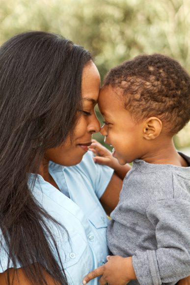 close up of an African American mom, forehead to forehead with her toddler son in her arms