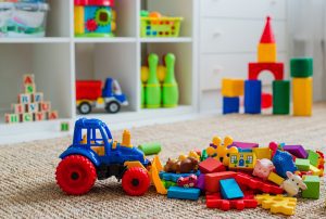 toys on the floor in a playroom with shelves of toys in the background