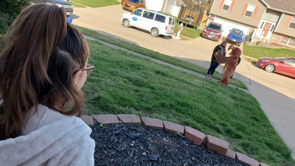 little girl watches Easter Bunny delivery from porch