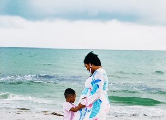 a mom and her son standing at the shore as a photo is taken