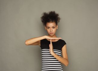 an African American woman in a black and white striped dress holding up her hands in the "timeout" signal