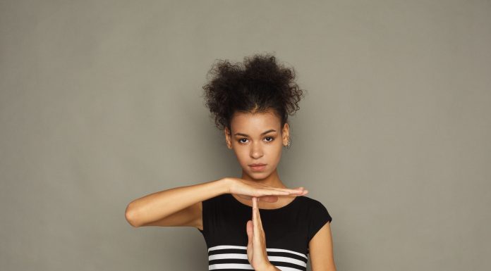 an African American woman in a black and white striped dress holding up her hands in the "timeout" signal