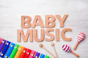 wooden letters that spell "baby music" next two a xylophone and maracas
