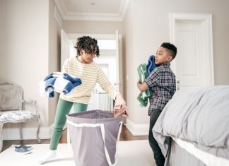 two kids putting laundry from the basket away
