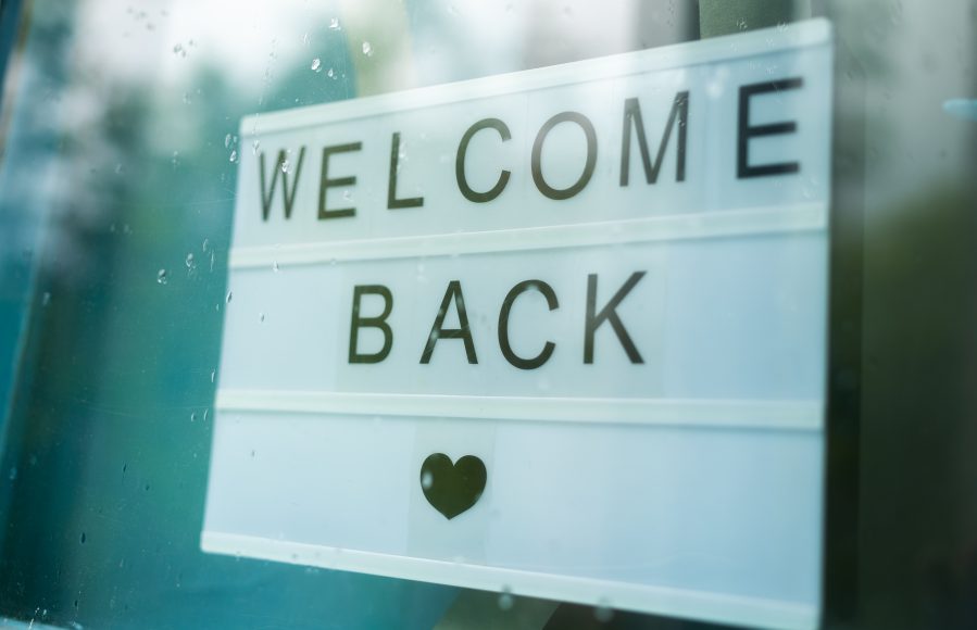 a sign in a window saying, "welcome back" with a heart underneath