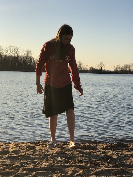 a girl walking barefoot up the sand, away from Creve Coeur Lake in Saint Louis