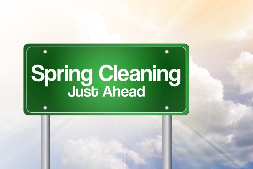 a green road sign that says Spring Cleaning Just Ahead 