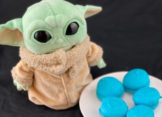 a baby Yoda stuffed toy next to a plate of blue macarons in honor of May the Fourth