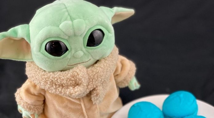 a baby Yoda stuffed toy next to a plate of blue macarons in honor of May the Fourth