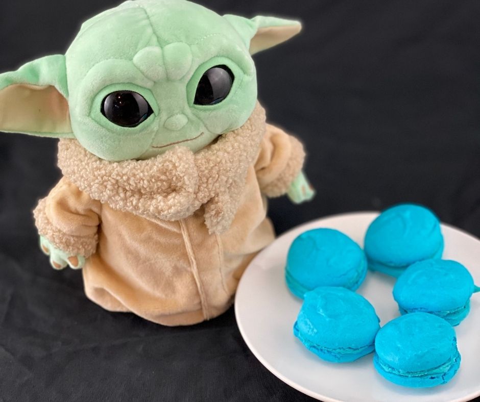 a Star Wars stuffed toy next to a plate of blue macarons in honor of May the Fourth