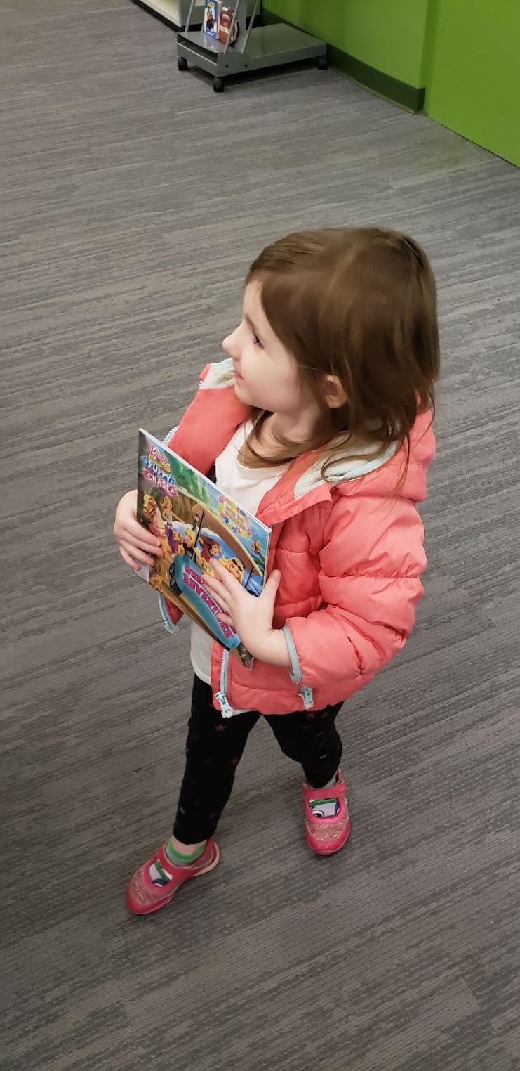 a little girl holding books at the library