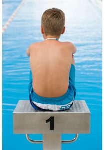 a photo of a boy from the back sitting on a diving platform