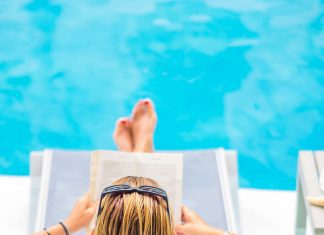 a woman in a lounge chair by the pool, reading a book