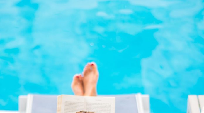 a woman in a lounge chair by the pool, reading a book