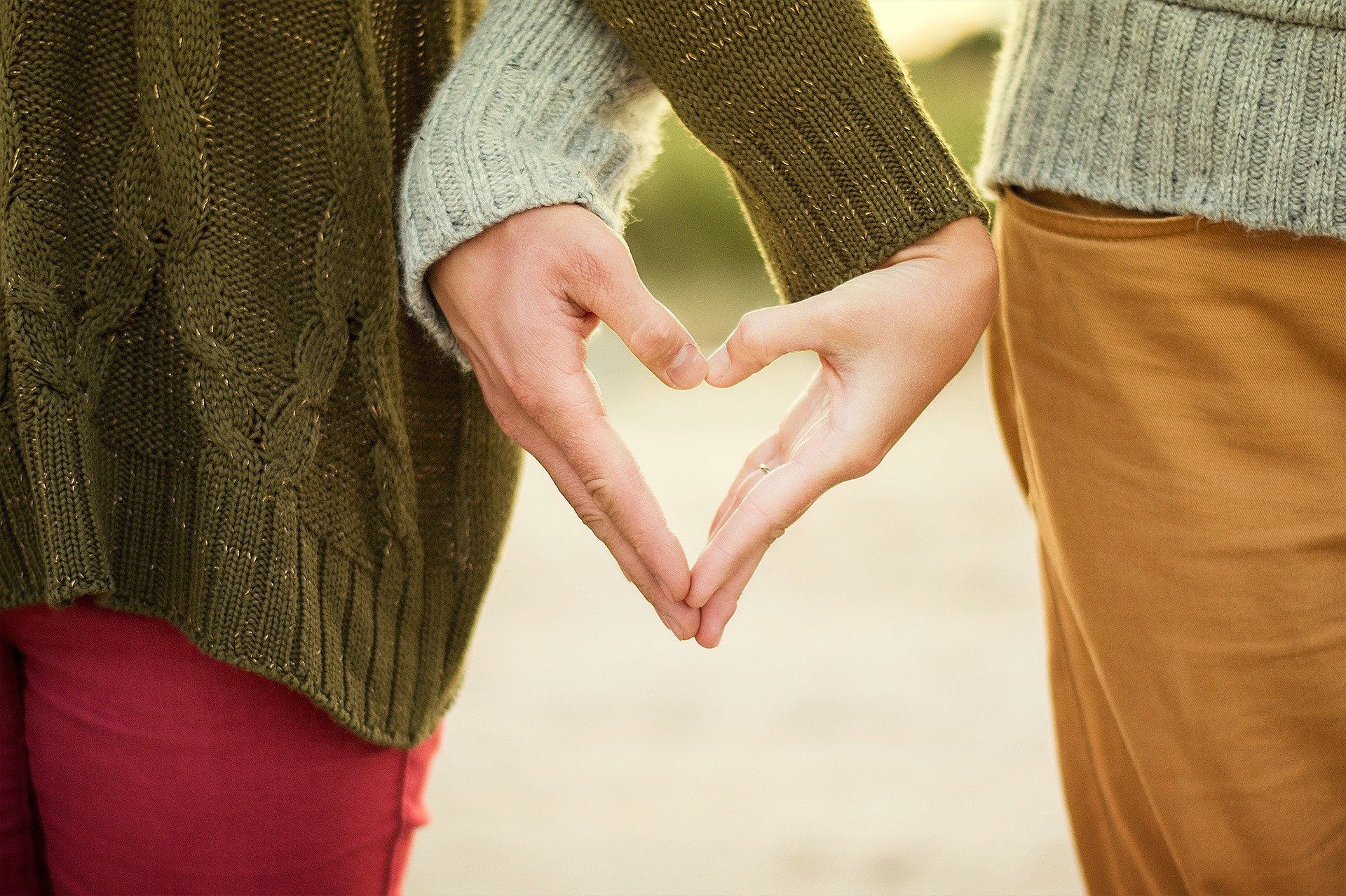 a close up of a couple holding their hands together in the shape of a heart, to represent love as their family motto