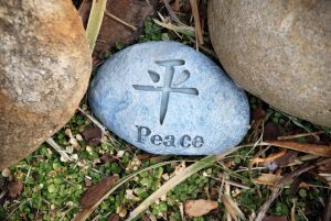 a stone in the grass with the word “Peace” in English and Chinese 