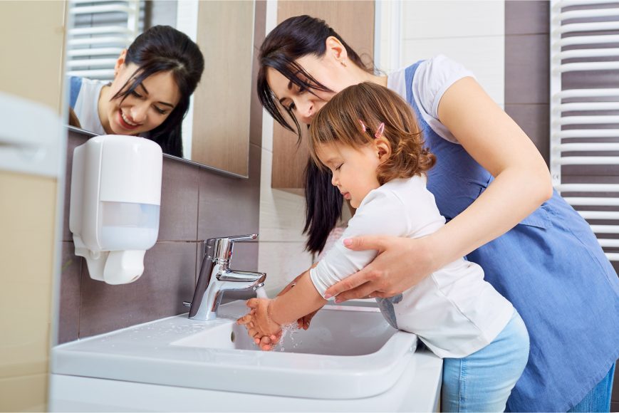 a mom helping her child wash hands to keep germs away