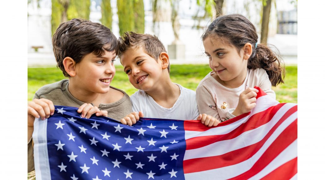 three kids holding an American flag for Fourth of July