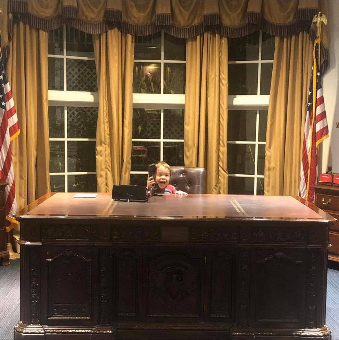 a child sitting at a desk in a replica of the Oval Office at the Magic House in Kirkwood, MO