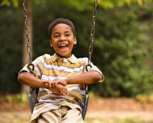 an African American boy on a swing at a playground