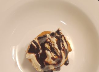 a warm chocolate chip cookie topped with Hudsonville Ice Cream and chocolate sauce