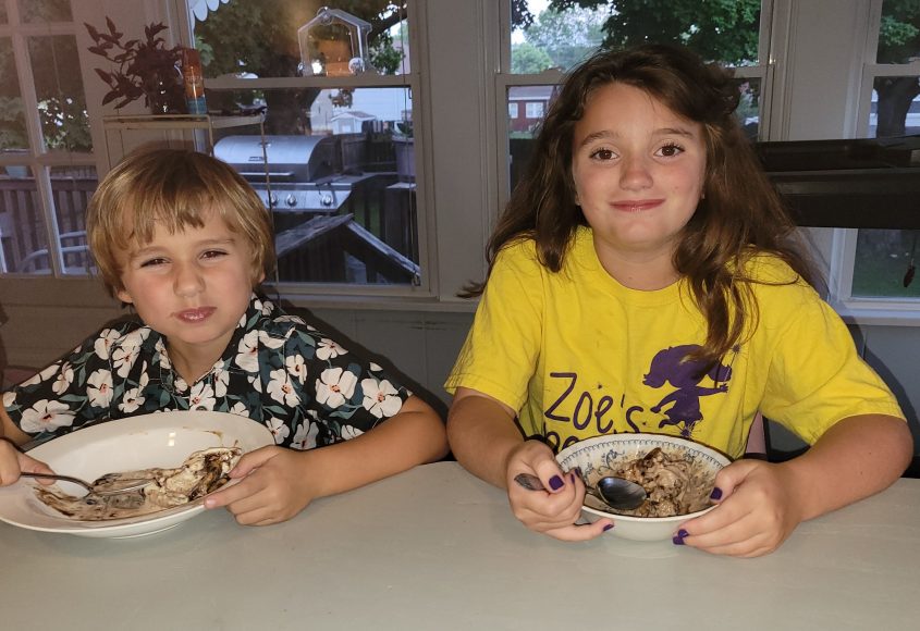 a boy and a girl sitting at a counter as they enjoy bowls of Hudsonville Ice Cream