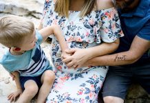a little boy putting his hand on his mom’s pregnant belly as she gets ready for a C-section