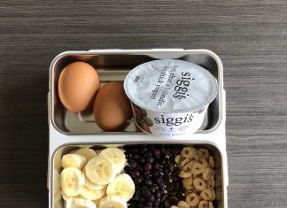 a bento box with banana slices, hard boiled eggs, yogurt, and cereal for feeding children healthy food