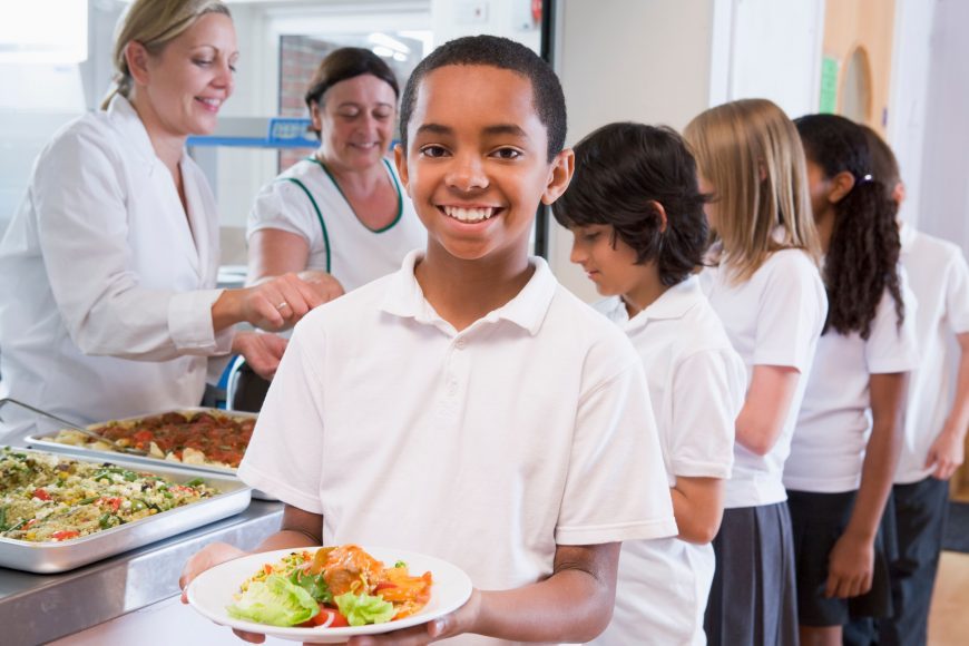 a line in the lunchroom of kids being served lunch