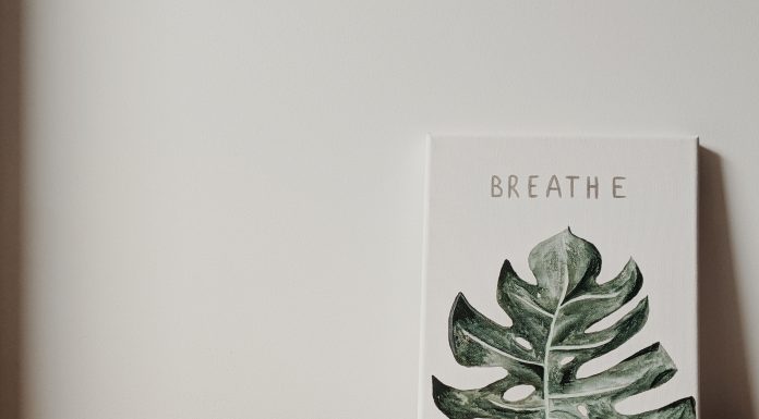a canvas on a table with the painting of a green leaf and the word, “Breathe” above it reminding us that it is okay to step back