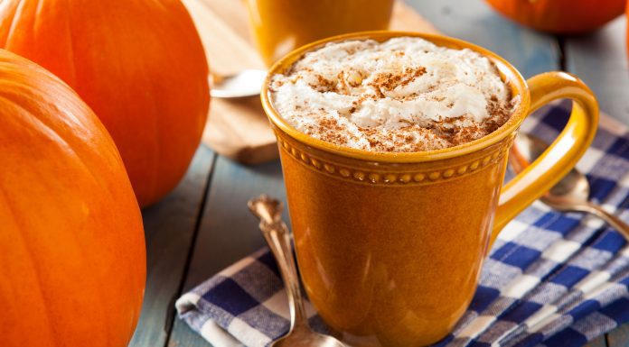 a pumpkin spice latte in a mug on a table next to pumpkins