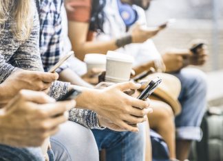 a close up of a group of friends, all staring down at their phones