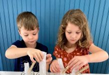 a boy and a girl conducting science activities with leaves using four mason jars with leaves in them and strips of coffee filters