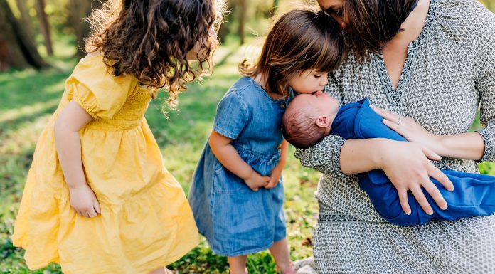 a mom holding her newborn son as her two daughters look on