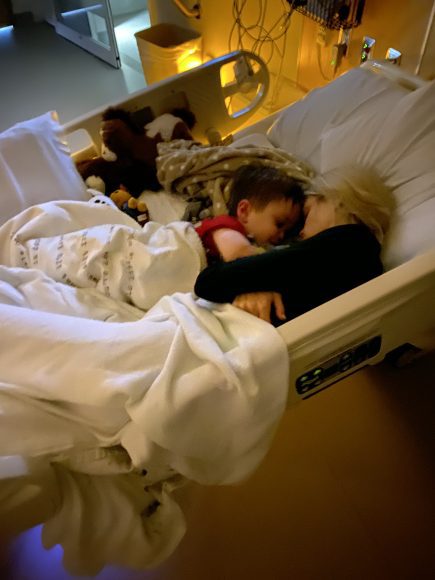 a mom snuggled up in a hospital bed with her child who is in need of pediatric medicine