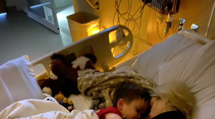 a mom snuggled up in a hospital bed with her child