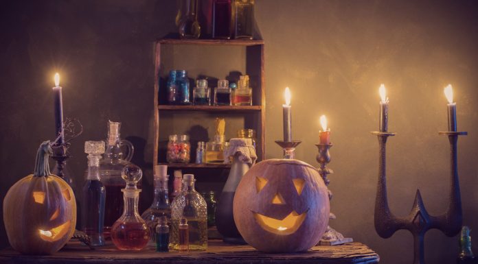 a table with bottles of potions, flanked by lit up jack-lanterns as candles flicker in the background