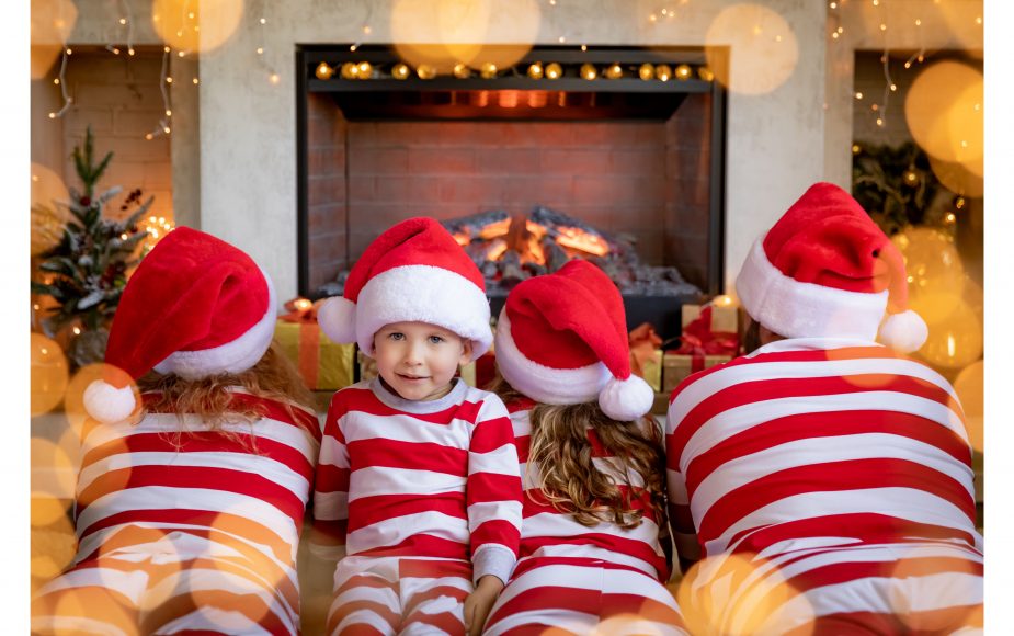 a family laying in front of the fireplace in matching red and white striped Christmas pajamas
