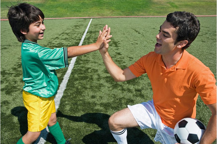 soccer coach high giving a young boy on the soccer field