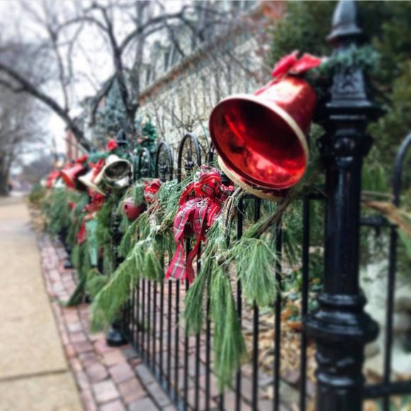 a wrought iron fence in Lafayette Square in St. Louis decked out with holiday greenery and red bells