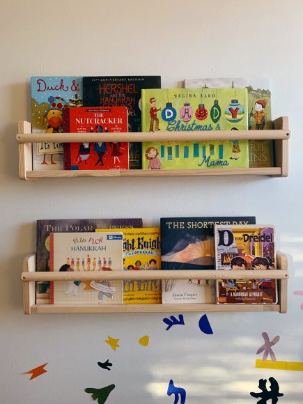 shelves in the home of an interfaith family filled with diverse books about both Hanukkah and Christmas