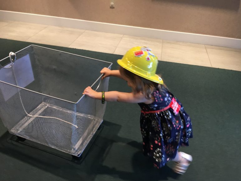 a toddler pushing an empt cart that will be filled with birthday gifts at the Magic House in Kirkwood, MO