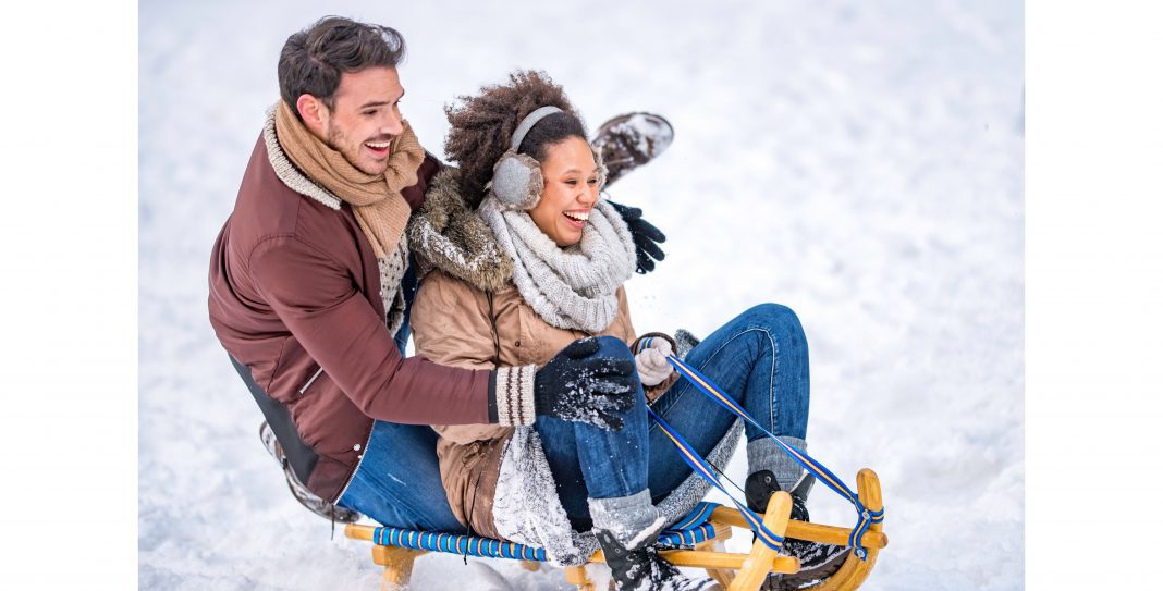 close up of a man and a woman sledding down a hill on a wooden sled